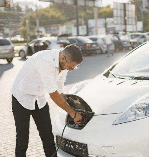 Young adult man charging his electric car